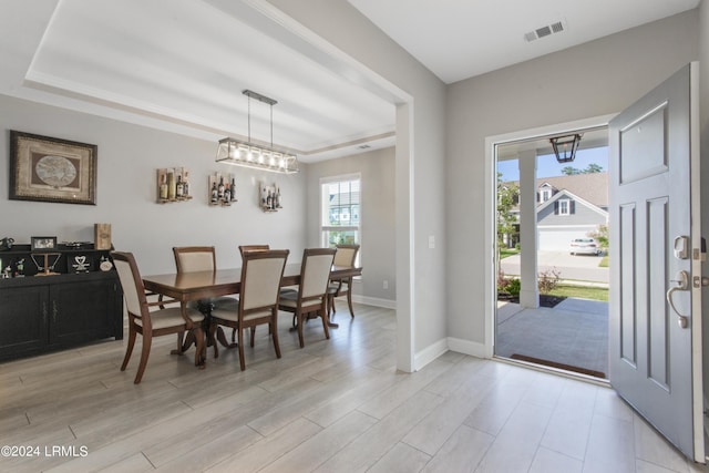 dining room featuring a tray ceiling and light hardwood / wood-style flooring