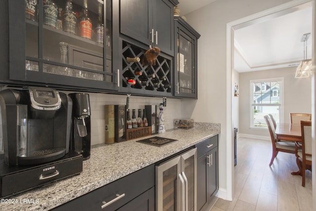 bar featuring wine cooler, light stone countertops, and tasteful backsplash