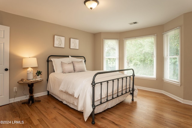 bedroom with hardwood / wood-style floors and multiple windows