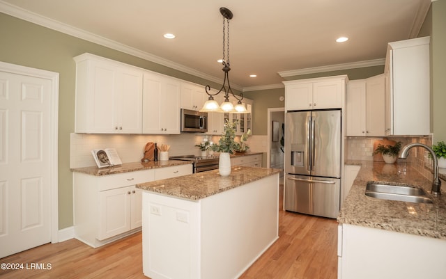 kitchen featuring sink, white cabinetry, stainless steel appliances, a kitchen island, and decorative light fixtures