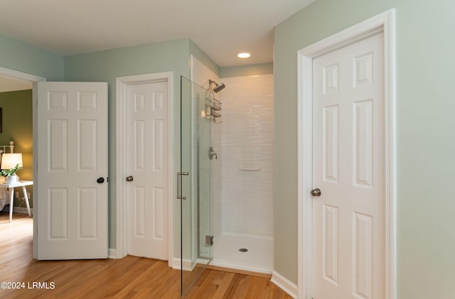 bathroom featuring hardwood / wood-style flooring and a shower with door