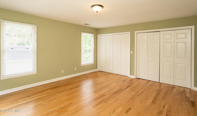 unfurnished bedroom featuring two closets and light hardwood / wood-style floors