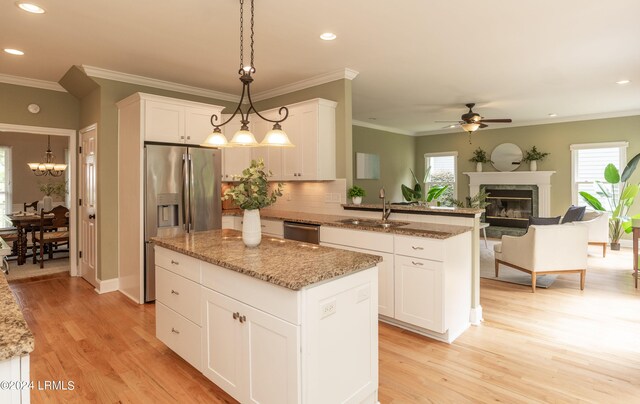 kitchen with white cabinetry, sink, decorative light fixtures, and a center island