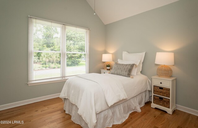 bedroom featuring vaulted ceiling, multiple windows, and light wood-type flooring