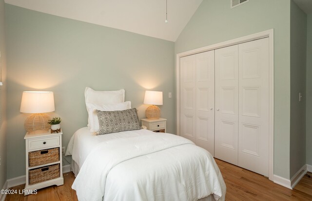 bedroom with lofted ceiling, light wood-type flooring, and a closet