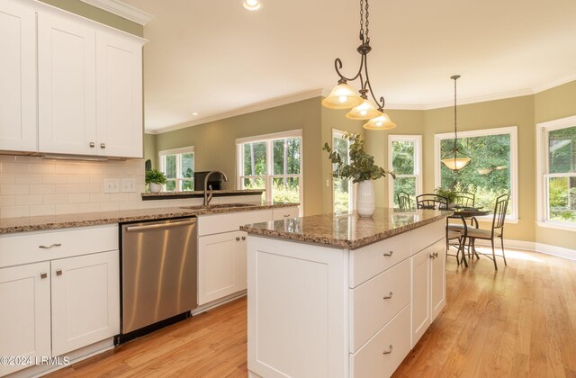 kitchen with sink, decorative light fixtures, a center island, stainless steel dishwasher, and dark stone counters