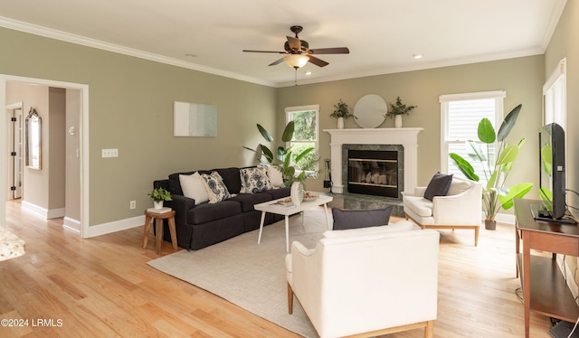 living room featuring light hardwood / wood-style flooring, a fireplace, a wealth of natural light, and ornamental molding