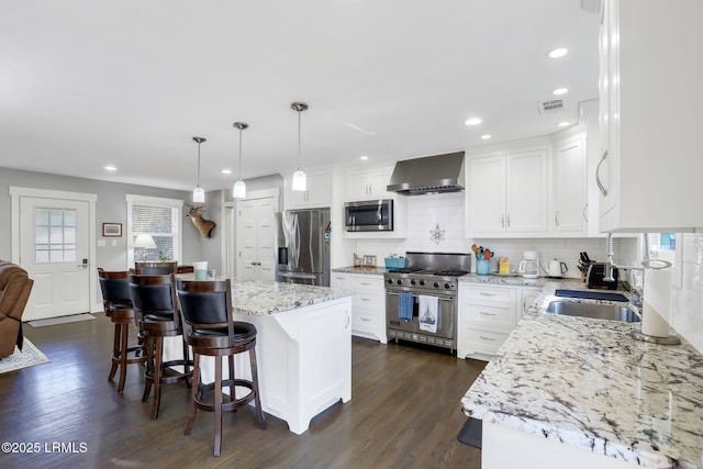 kitchen with a wealth of natural light, visible vents, appliances with stainless steel finishes, and wall chimney range hood