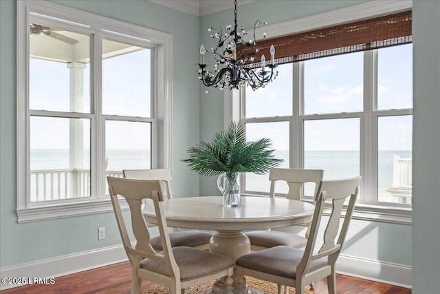 dining space featuring a water view, baseboards, and dark wood finished floors