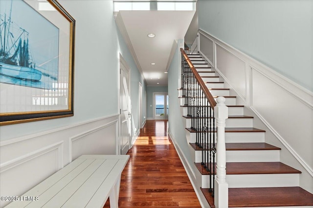 stairway with recessed lighting, a decorative wall, and wood finished floors