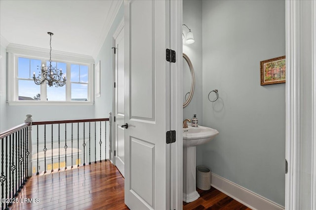 bathroom featuring a sink, wood finished floors, baseboards, an inviting chandelier, and crown molding