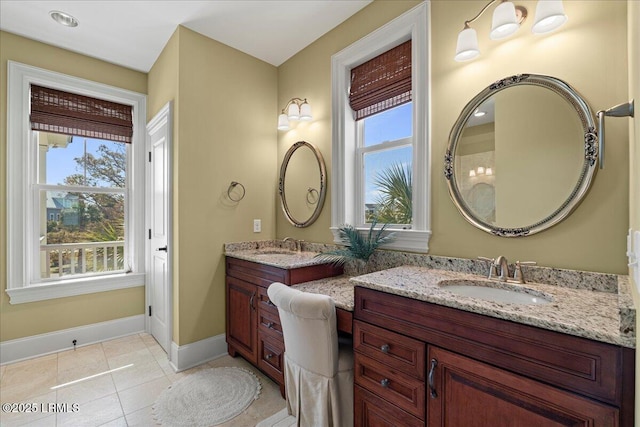 full bathroom with double vanity, tile patterned flooring, a sink, and baseboards