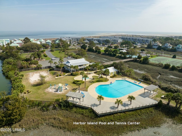 pool featuring a water view, a patio area, fence, and an outdoor structure