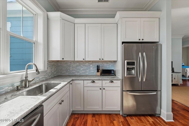 kitchen featuring tasteful backsplash, dark wood-style floors, appliances with stainless steel finishes, ornamental molding, and a sink