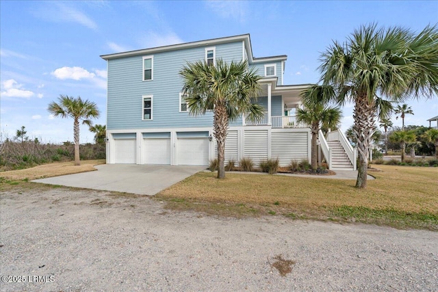 view of front of property featuring concrete driveway, covered porch, a front yard, a garage, and stairs