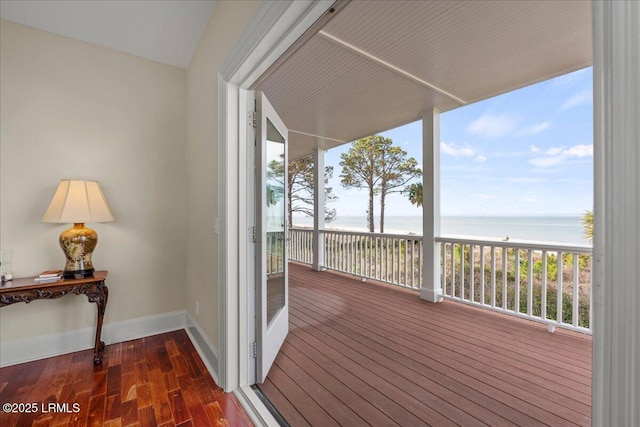 wooden terrace with a water view and a view of the beach