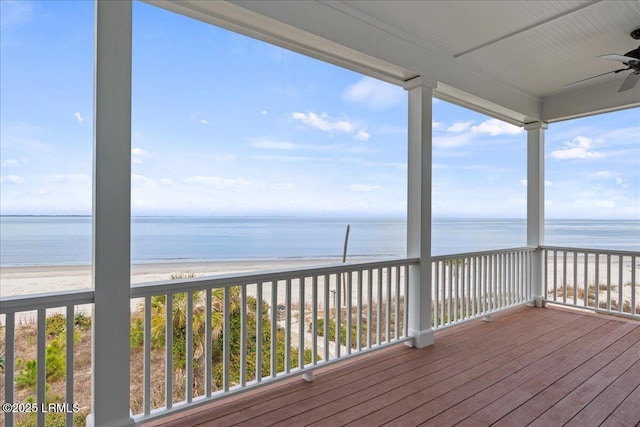 deck with a water view, a view of the beach, and a ceiling fan