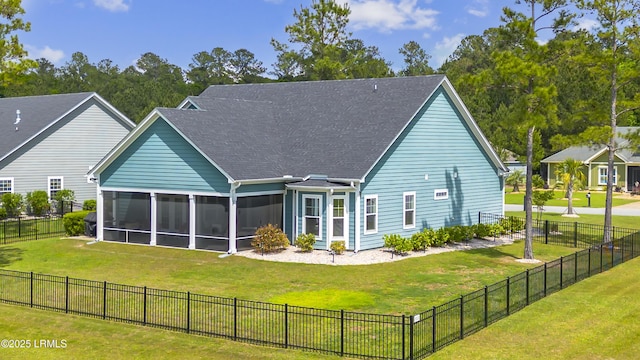 rear view of property featuring fence, roof with shingles, a sunroom, and a lawn