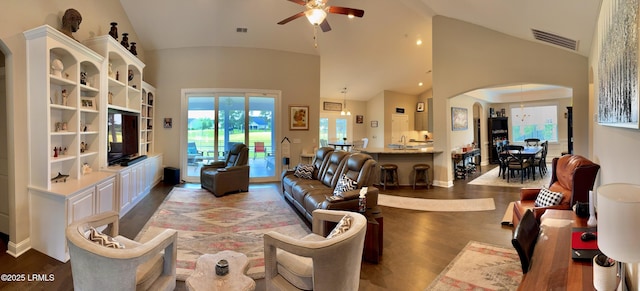 living area with baseboards, visible vents, ceiling fan, arched walkways, and wood finished floors