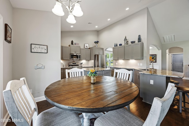 dining room with a chandelier, arched walkways, dark wood-style floors, and recessed lighting