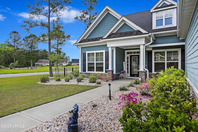 view of front facade featuring a standing seam roof, stone siding, a front lawn, and metal roof