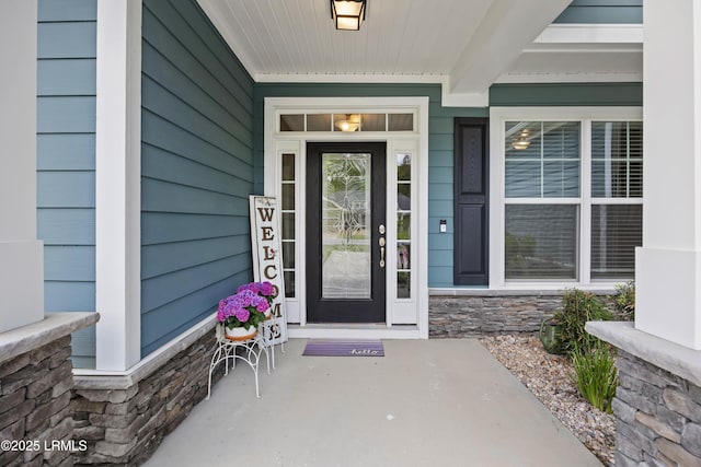 view of exterior entry featuring a porch and stone siding