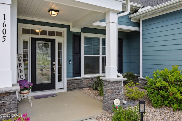 view of exterior entry with a porch and stone siding
