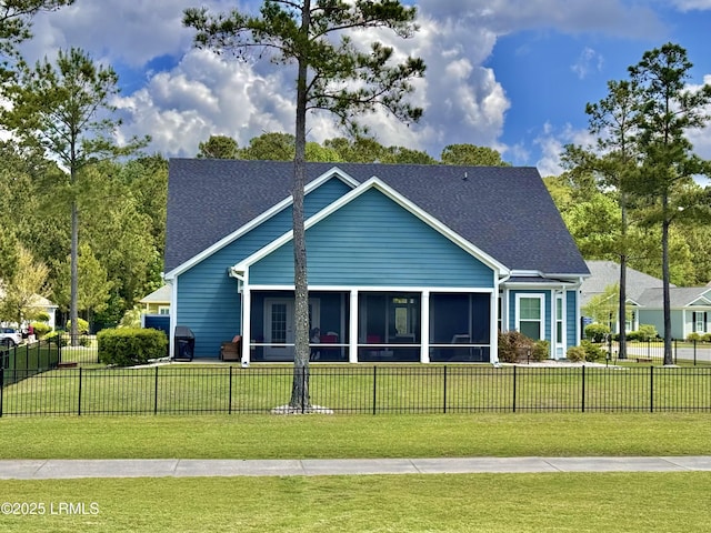 view of front facade with a shingled roof, a sunroom, a front lawn, and a fenced front yard