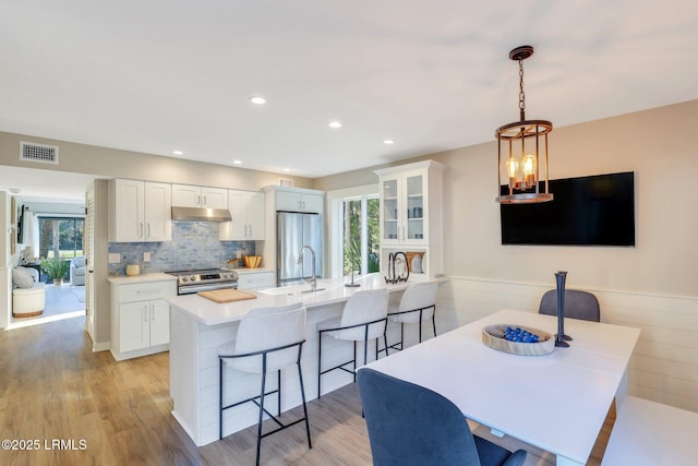 kitchen with pendant lighting, a healthy amount of sunlight, a breakfast bar area, and white cabinets