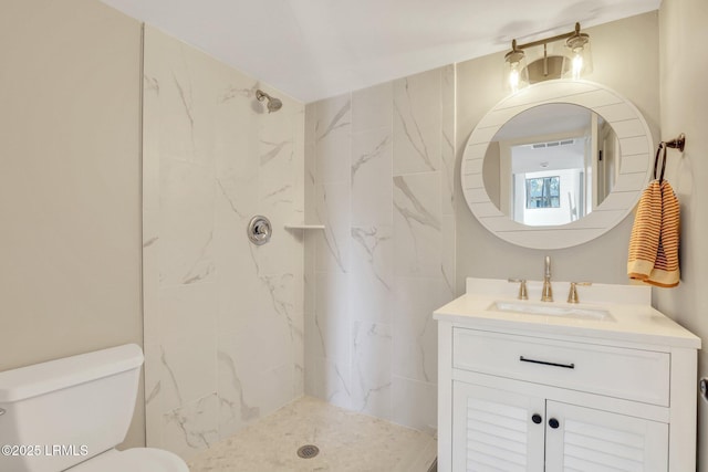 bathroom featuring vanity, a tile shower, and toilet