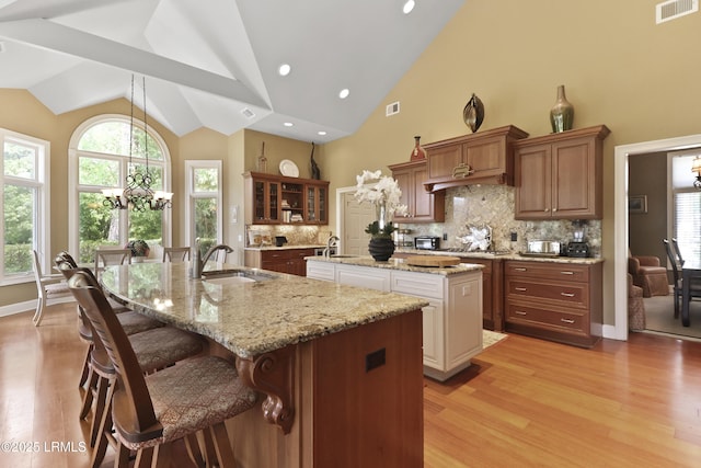 283 Seabrook Dr, Hilton Head Island, SC 29926 - kitchen with a kitchen island with sink, a sink, light wood-style flooring, tasteful backsplash, and a breakfast bar