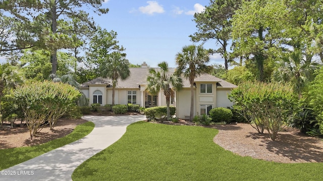 283 Seabrook Dr, Hilton Head Island, SC 29926 - view of front of house featuring stucco siding, a front yard, and a chimney