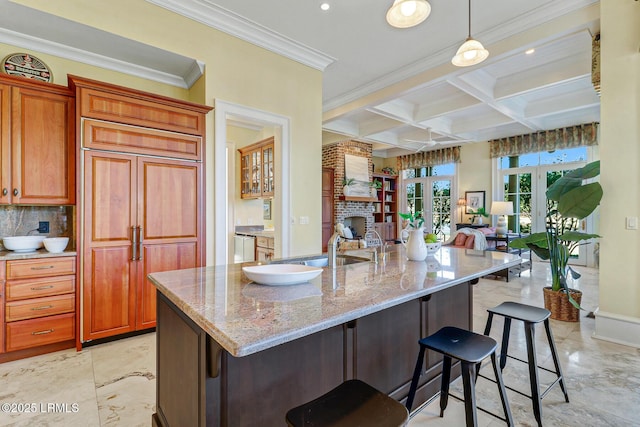 kitchen featuring paneled refrigerator, a breakfast bar area, coffered ceiling, open floor plan, and beam ceiling