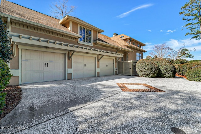 view of front facade with a garage, driveway, roof with shingles, and stucco siding