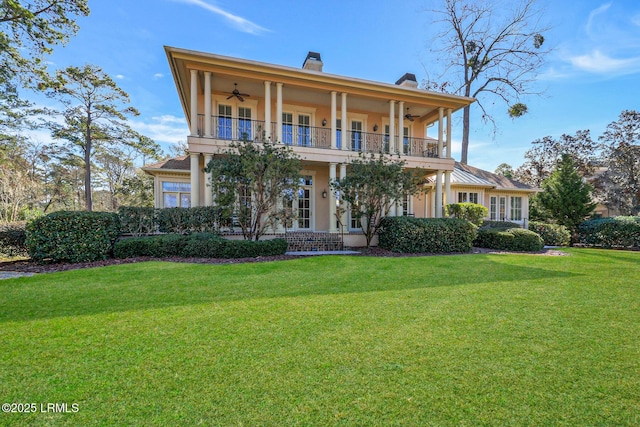 view of front of property with ceiling fan, a front lawn, and a balcony