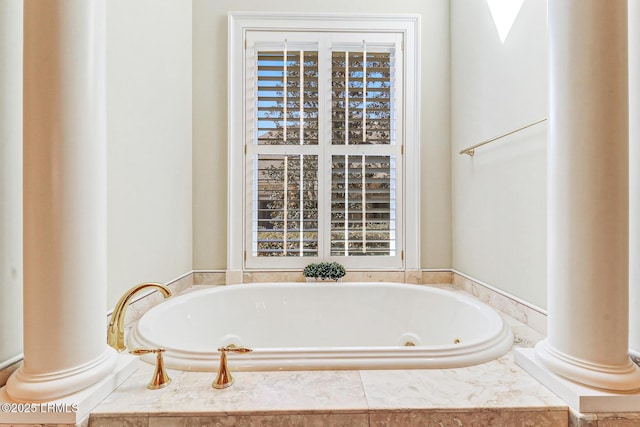 bathroom featuring a whirlpool tub and decorative columns