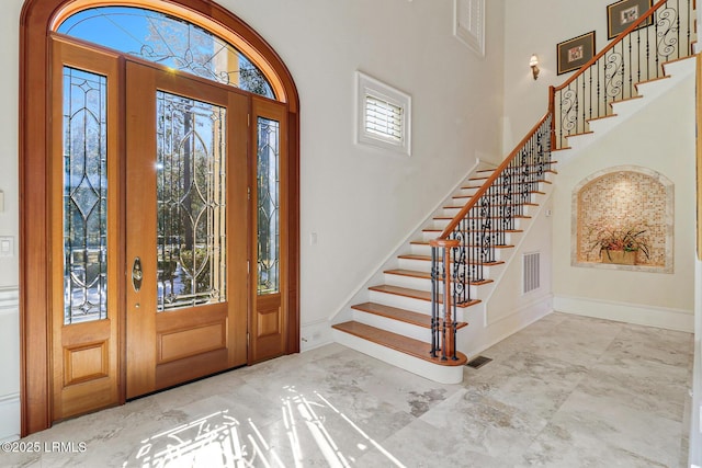 entryway featuring french doors, visible vents, a high ceiling, baseboards, and stairs