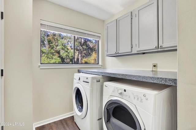 laundry room with dark hardwood / wood-style floors, washing machine and dryer, and cabinets