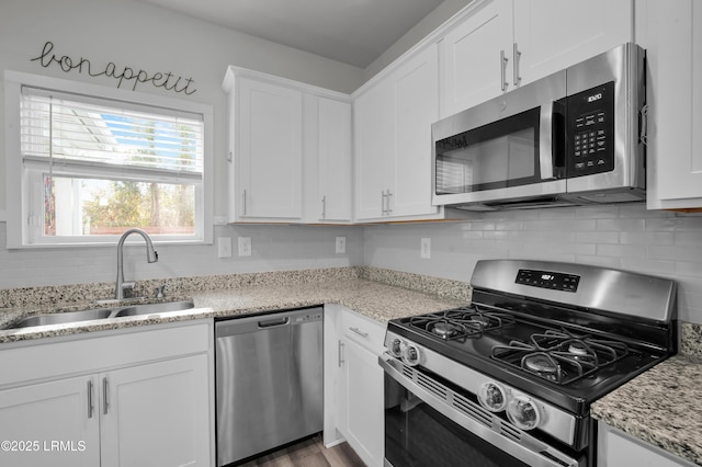 kitchen with white cabinets, backsplash, appliances with stainless steel finishes, and a sink