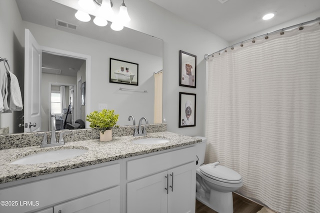 bathroom with double vanity, toilet, visible vents, and a sink