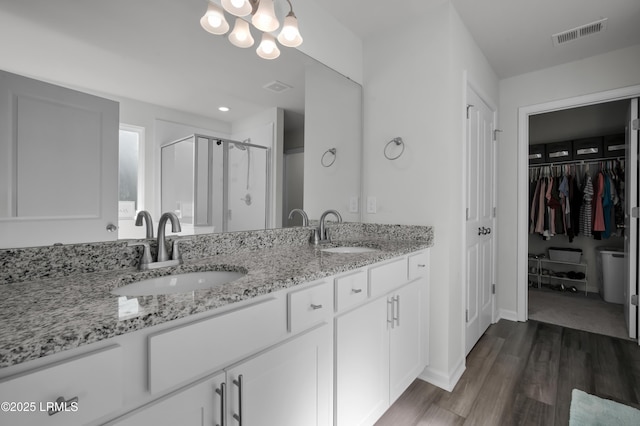 full bathroom featuring double vanity, visible vents, a stall shower, and a sink