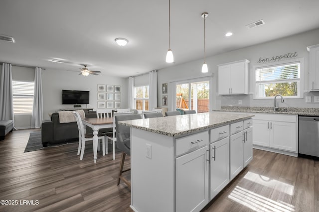 kitchen featuring visible vents, a ceiling fan, a sink, stainless steel dishwasher, and a center island