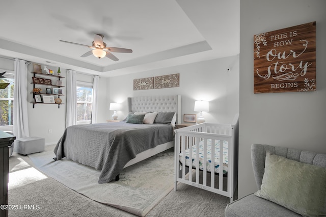 bedroom featuring baseboards, carpet flooring, a ceiling fan, and a tray ceiling