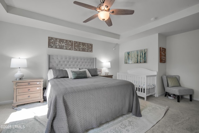 bedroom featuring baseboards, a raised ceiling, carpet, and ceiling fan