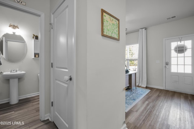 foyer entrance featuring visible vents, baseboards, and wood finished floors