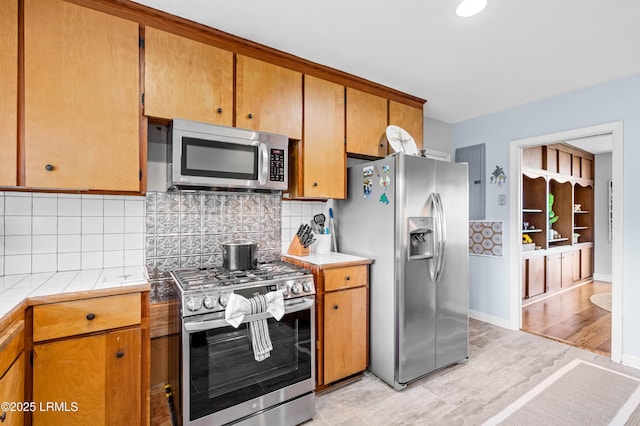 36 Stuart Town Ct, Beaufort, SC 29902 - kitchen featuring appliances with stainless steel finishes, decorative backsplash, tile countertops, baseboards, and light wood-style flooring