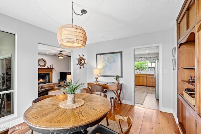 36 Stuart Town Ct, Beaufort, SC 29902 - dining space featuring a ceiling fan, light wood-type flooring, a lit fireplace, baseboards, and a chandelier
