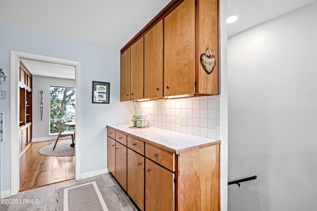 36 Stuart Town Ct, Beaufort, SC 29902 - kitchen with tile counters, backsplash, baseboards, light wood-style flooring, and brown cabinets