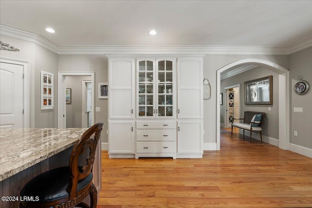 dining area with ornamental molding and light hardwood / wood-style flooring