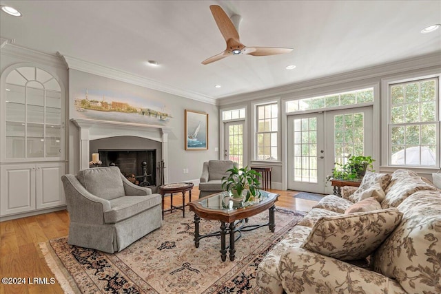 living room with crown molding, ceiling fan, french doors, and light wood-type flooring